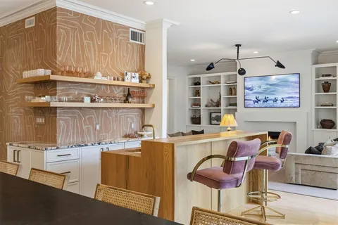 a room with a dining table wooden floor and cabinets