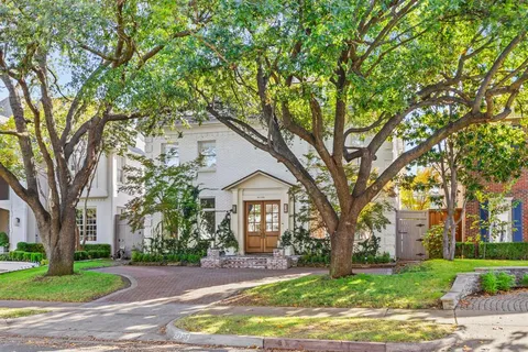 a front view of a house with a garden and trees