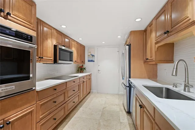 a kitchen with stainless steel appliances granite countertop a sink and a refrigerator