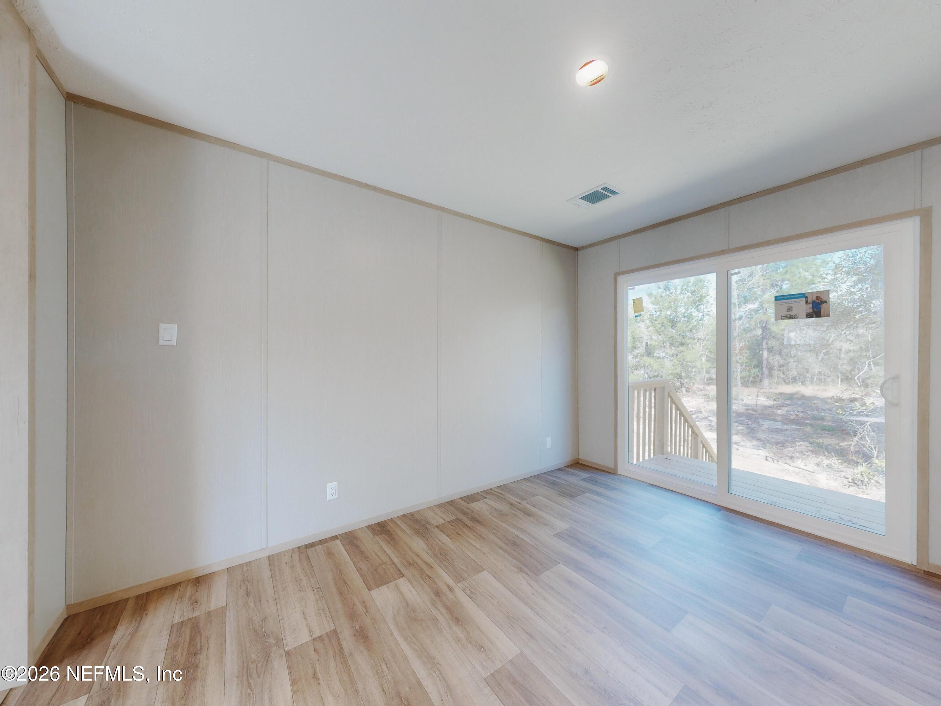 5770 Acadia Street Keystone Heights, FL 32656 - Photo 13 of 64 a view of an empty room with wooden floor and a window