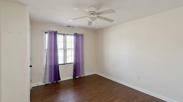 an empty room with wooden floor and windows
