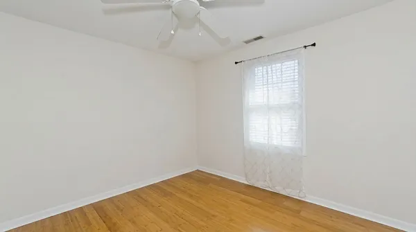 an empty room with wooden floor and windows