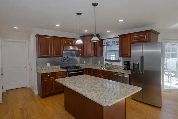 a kitchen with stainless steel appliances granite countertop a sink a stove a refrigerator and a center island