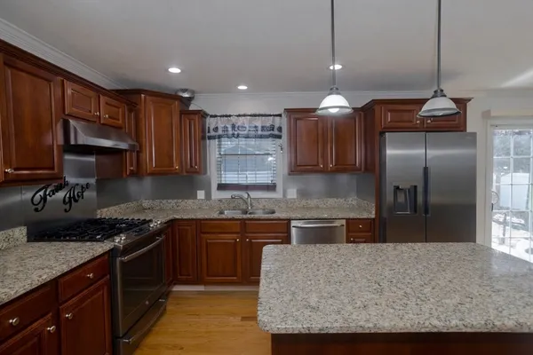 a kitchen with stainless steel appliances granite countertop a sink a stove and a refrigerator