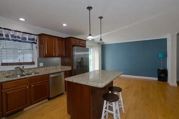 a kitchen with stainless steel appliances granite countertop a sink a refrigerator and wooden cabinets