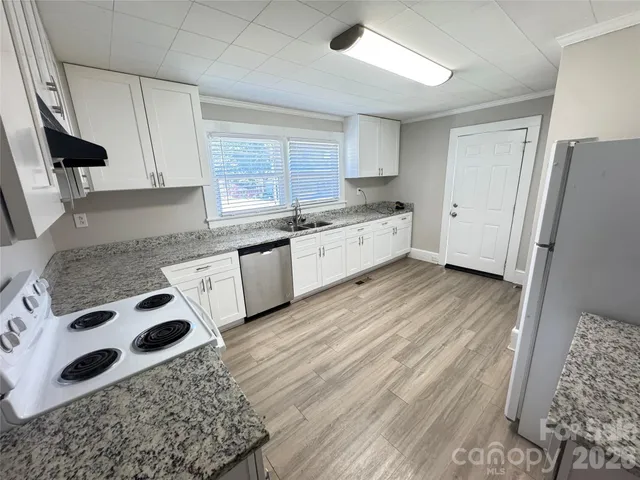 a kitchen with stainless steel appliances granite countertop a sink a stove a refrigerator and cabinets