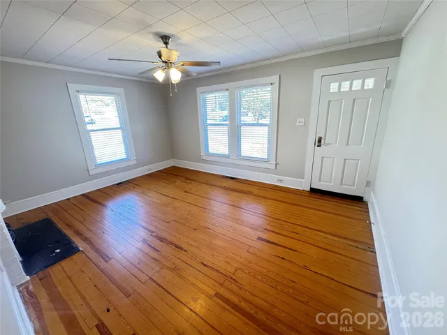 a view of an empty room with wooden floor and a window