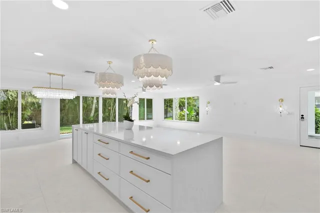 an open kitchen with granite countertop a stove and a white kitchen island
