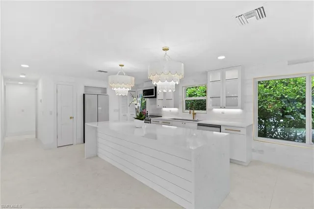 a large white kitchen with a large window and stainless steel appliances