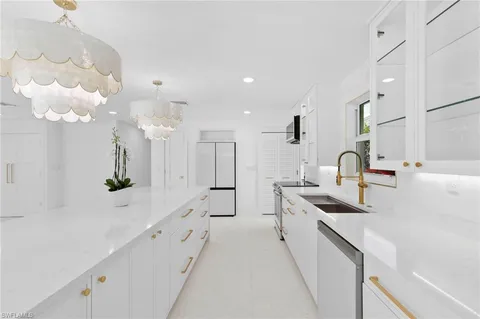 a large white kitchen with lots of counter space and sink