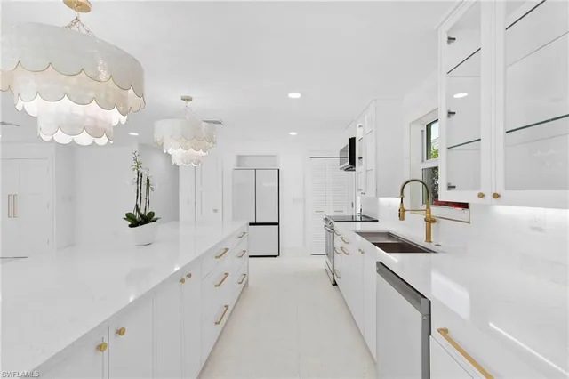 a large white kitchen with lots of counter space and sink