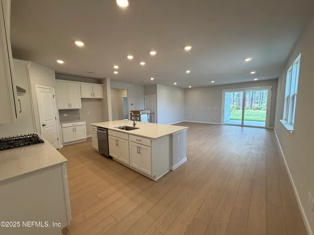 a kitchen with white cabinets and a stove with wooden floor