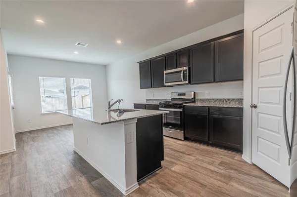 a kitchen with stainless steel appliances granite countertop a stove a sink and a microwave