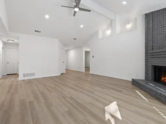 a view of empty room with wooden floor and fireplace