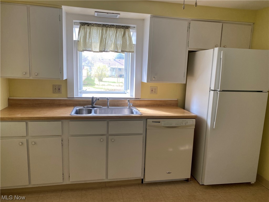 1016 Mannering Road Eastlake, OH 44095 - Photo 9 of 24 Kitchen with light tile flooring, sink, white appliances, and white cabinetry