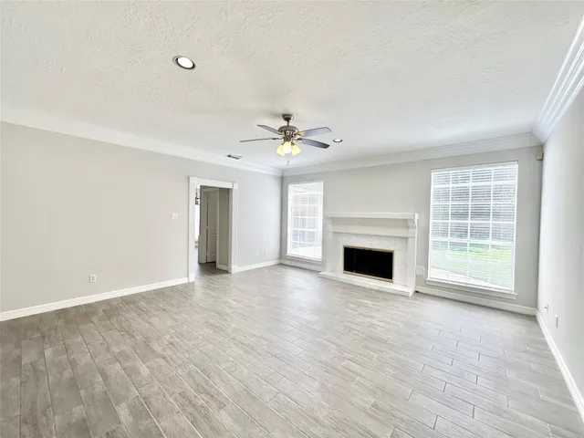 wooden floor fireplace and windows in an empty room