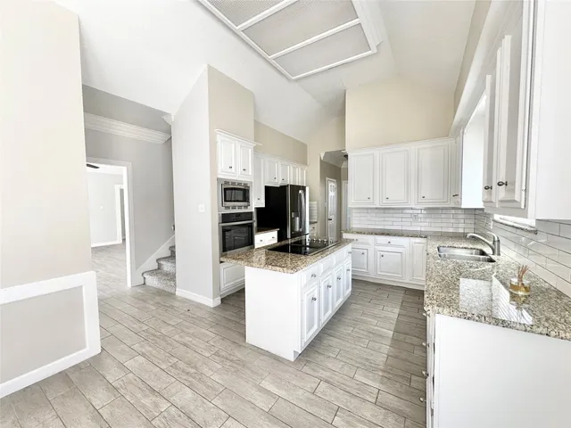 a kitchen with granite countertop a sink a counter top space and cabinets