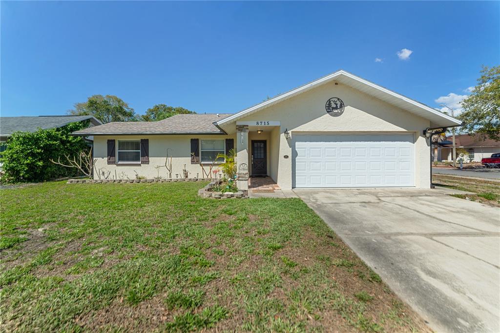 8715 Huntsman Lane Port Richey, FL 34668 - Photo 1 of 54 a front view of a house with a yard and garage
