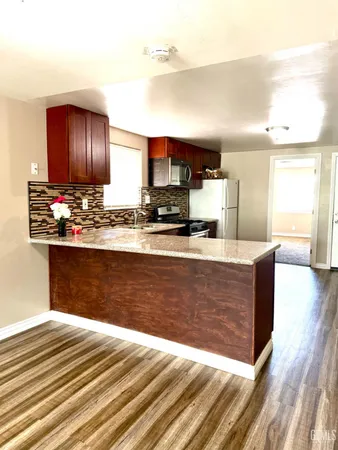 a view of kitchen with stainless steel appliances granite countertop cabinets and wooden floor