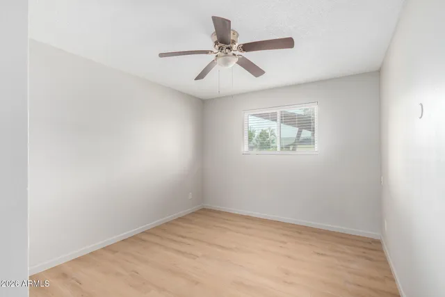 an empty room with a window and a fan