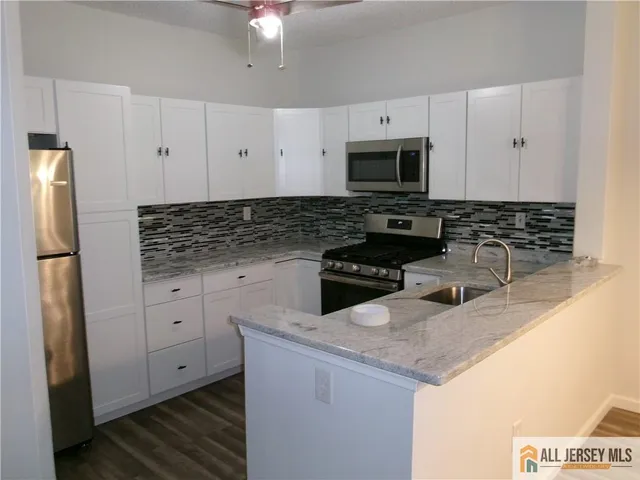 a kitchen with granite countertop a sink stainless steel appliances and white cabinets