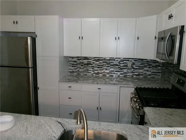 a kitchen with stainless steel appliances granite countertop a refrigerator sink and white cabinets