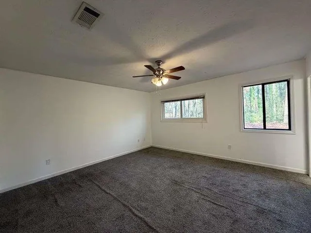 an empty room with windows and ceiling fan