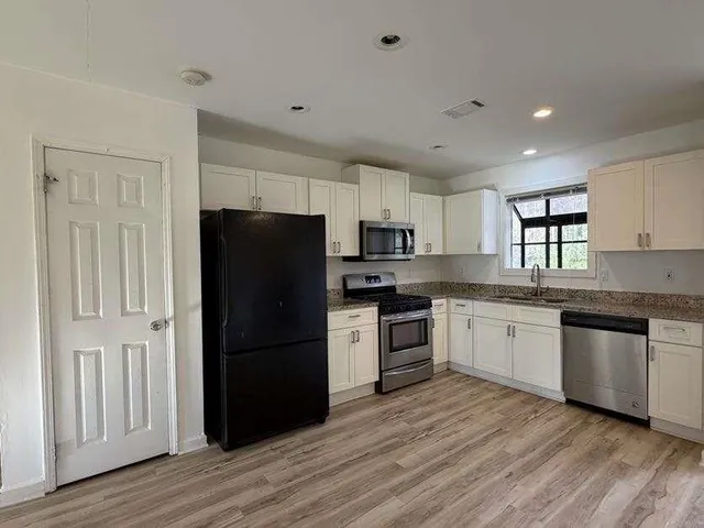 a kitchen with granite countertop a refrigerator stove top oven and sink