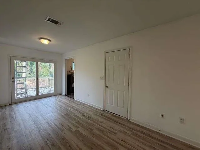 a view of an empty room with wooden floor and a window