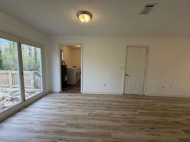 a view of an empty room with wooden floor and a window