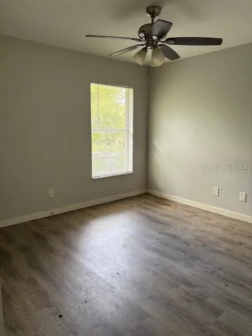 an empty room with a window and a fan