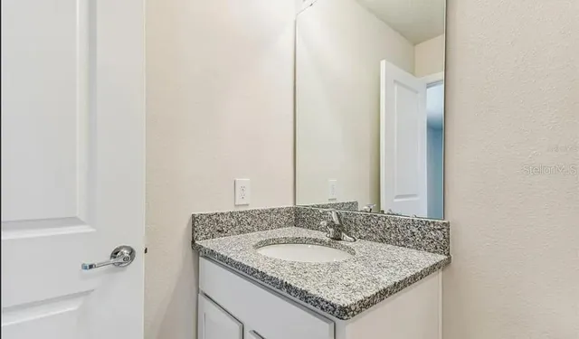 a bathroom with a granite countertop sink and a mirror