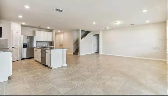 a view of kitchen with stainless steel appliances kitchen island granite countertop a stove a refrigerator a sink and a refrigerator with white cabinets