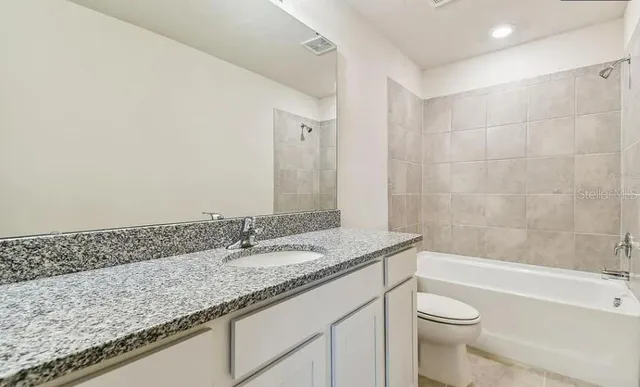 a bathroom with a granite countertop sink a toilet and bathtub