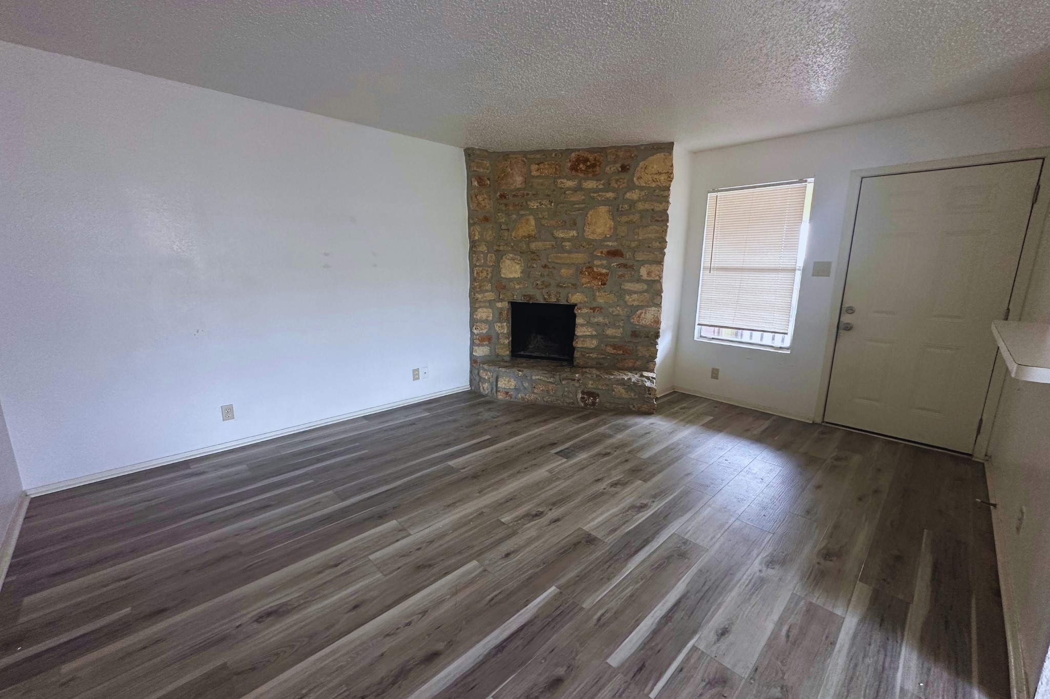 2202 Tabor Court, Unit C Austin, TX 78748 - Photo 2 of 14 Unfurnished living room with a stone fireplace, dark wood-style floors, and a textured ceiling