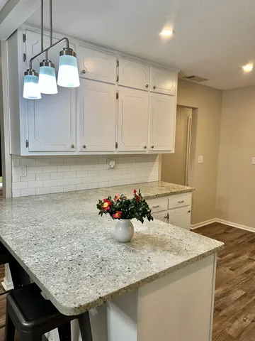 a kitchen with stainless steel appliances kitchen island granite countertop a sink dishwasher and cabinets with wooden floor