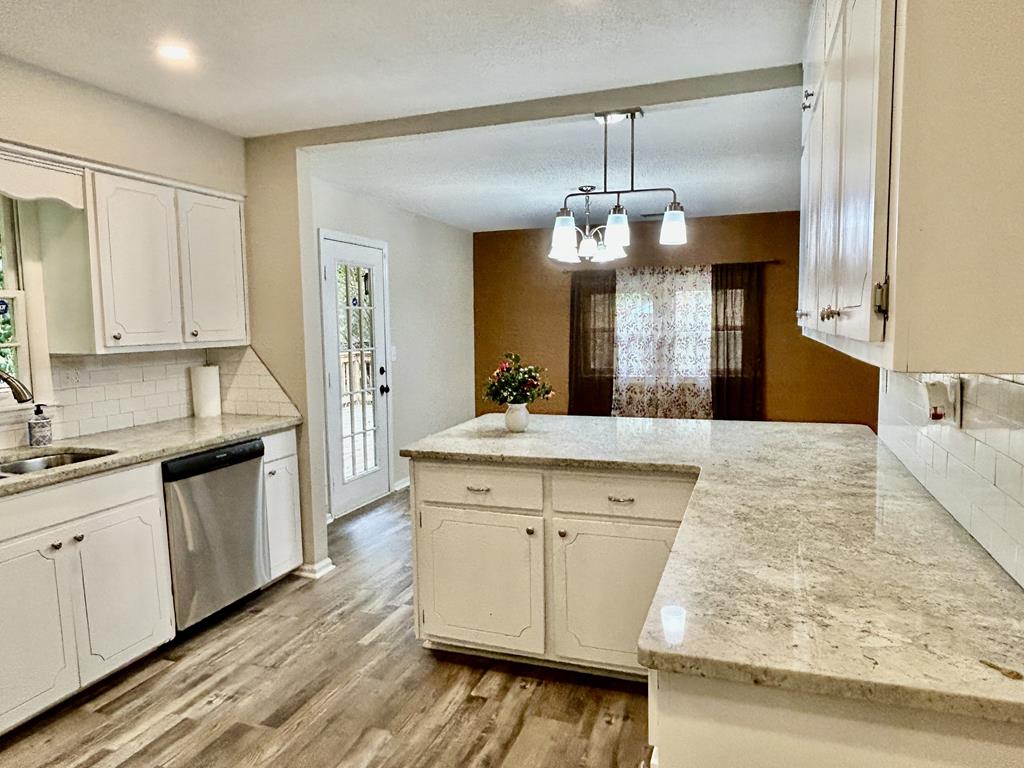 5636 Webb Avenue Columbus, GA 31909 - Photo 18 of 52 a kitchen with a sink dishwasher a stove and white cabinets with wooden floor