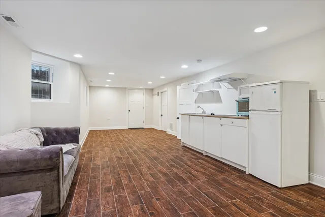 a view of kitchen and empty room with wooden floor