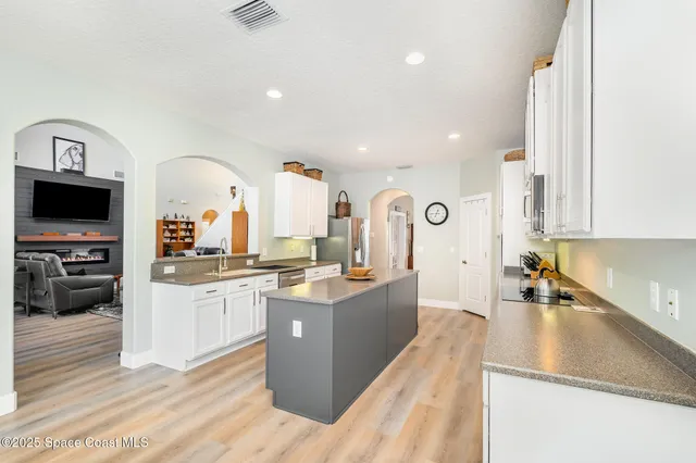 a large kitchen with stainless steel appliances granite countertop a lot of counter space and a wooden floor