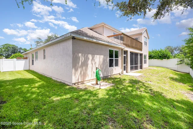 a white house that has a small yard and large trees