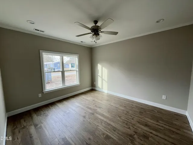 an empty room with wooden floor chandelier fan and windows