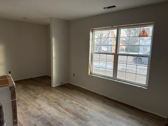 a view of an empty room with wooden floor and a window