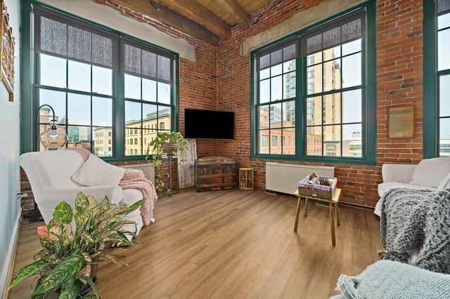 a living room with furniture two window and a wooden floor