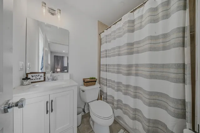 a bathroom with a granite countertop toilet a sink and a mirror
