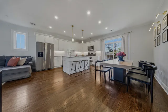 a living room with stainless steel appliances furniture and wooden floor