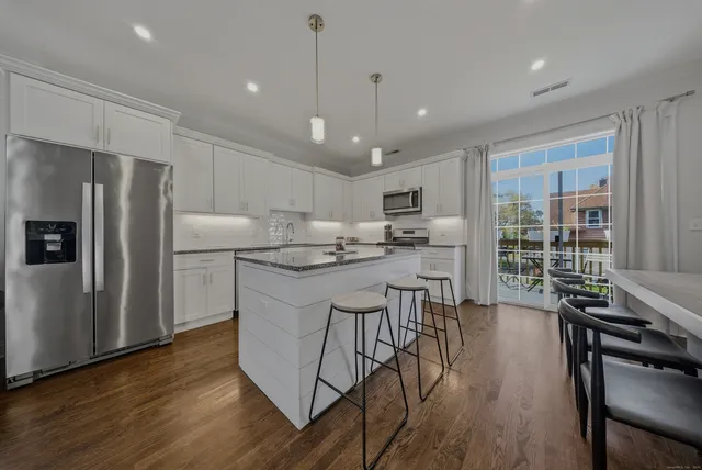 a kitchen with stainless steel appliances granite countertop a refrigerator a stove a sink dishwasher a oven with white cabinets and wooden floor