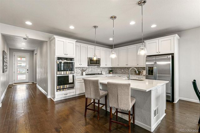 a kitchen with stainless steel appliances granite countertop a table chairs refrigerator and sink