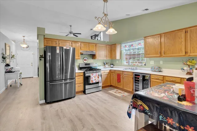 a kitchen with stainless steel appliances granite countertop a refrigerator a sink dishwasher a stove and a dining table with wooden floor