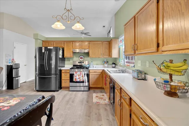 a kitchen with stainless steel appliances granite countertop a refrigerator a sink dishwasher a stove and a dining table with wooden floor