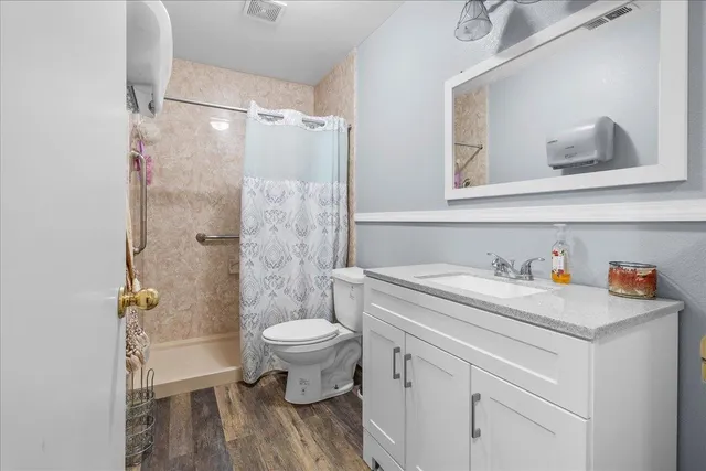 a bathroom with a granite countertop sink toilet a mirror and shower